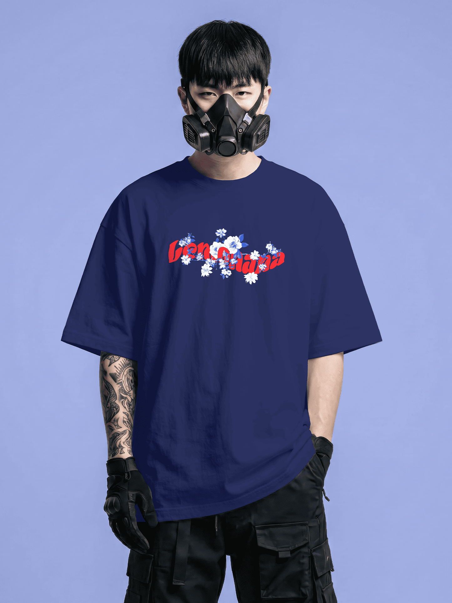 Person wearing a navy blue t-shirt with text and graphics, black pants, and a black mask on a blue background