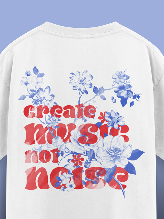 White t-shirt with floral design and text 'Create music, not noise' on a blue background