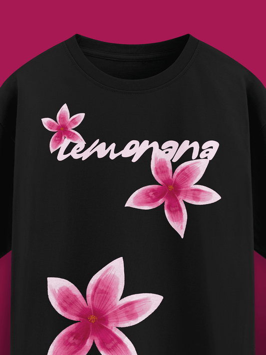 Black t-shirt with pink floral designs and 'tumamana' text on a magenta background
