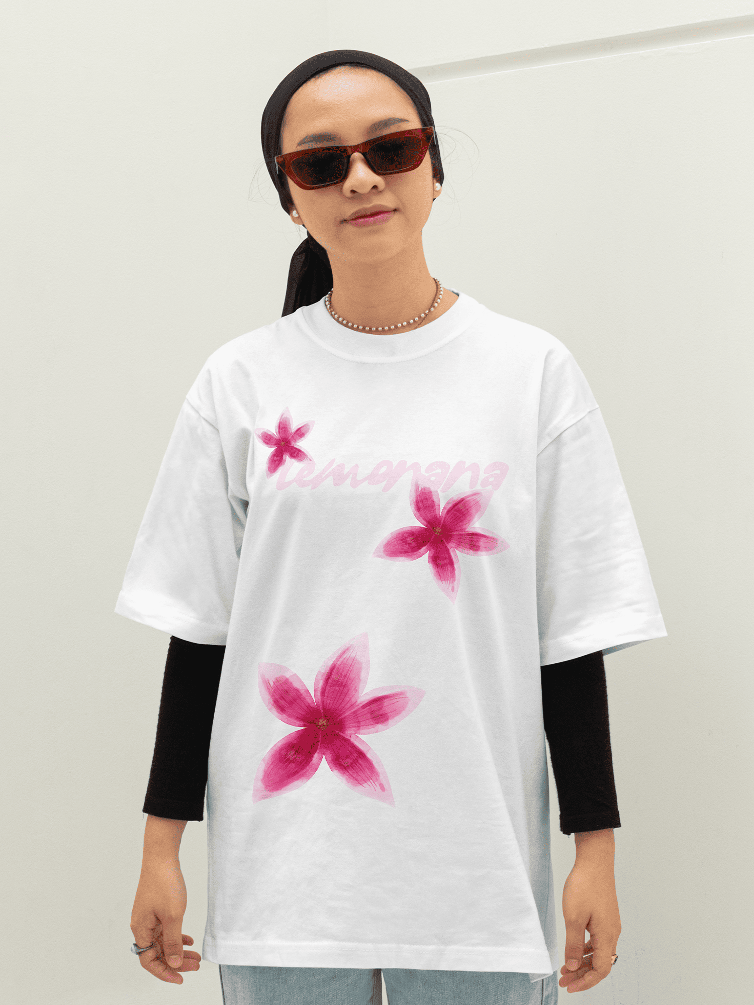 Person wearing a white t-shirt with pink floral designs on a plain background
